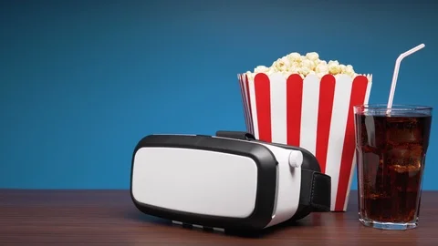 VR headset, a box of popcorn and a glass of cola drink with ice on the table. 4K Stock Footage 102276948