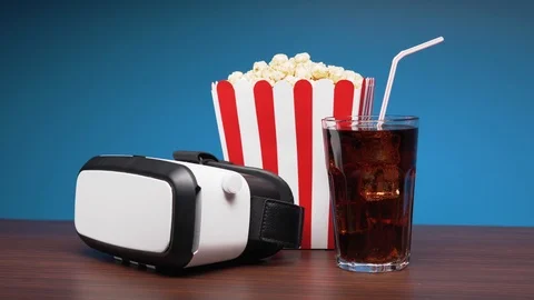 VR headset, a box of popcorn and a glass of cola drink with ice on the table. 4K Stock Footage 102276975