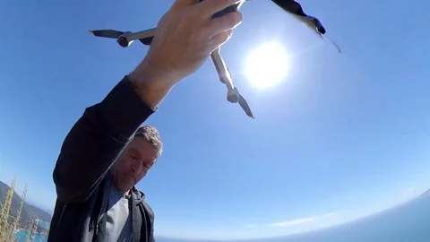 VR360 effect A man do a take off with a drone on a high cliff on sea Stock Footage 107192427