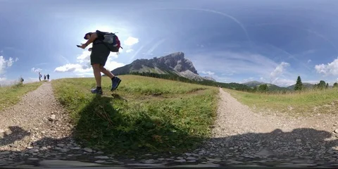 VR360 a Man does Trek walking on Alpine path backlight  POV Stock Footage 114076408