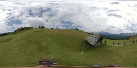 VR360 Some Trekkers walk on Alpine path in a wide green valley Video stock 114076296