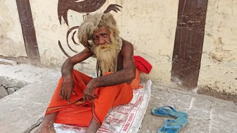 VRINDAVAN, INDIA- OCTOBER 12, 2025: Overgrown indian ascetic sitting by road Stock Footage 325212991