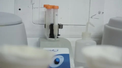 VWR analog vortex mixer vibrates and mixes four orange-capped test tubes Stock Footage 255759409