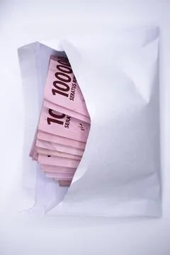 A wad of one hundred thousand rupiah bills folded in a white envelope Stock Photos