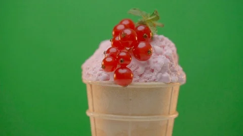 Waffle cone with cherry ice cream decorated with red currant and mint on green Stock Footage 109060508