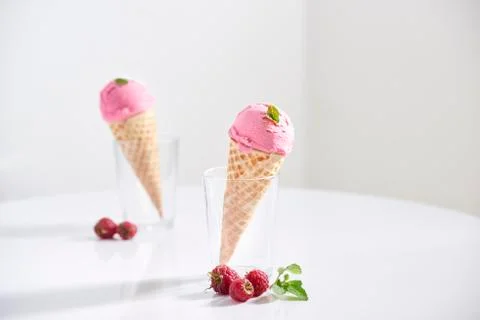 Waffle cone filled with fresh raspberry ice cream in glass cup with fresh ras Stock Photos