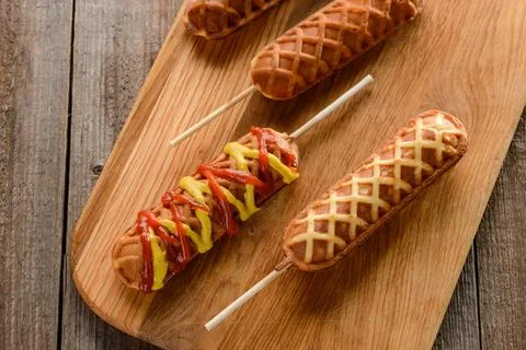 Waffle corn dogs decorated with zig zags of mustard and ketchup 스톡 사진
