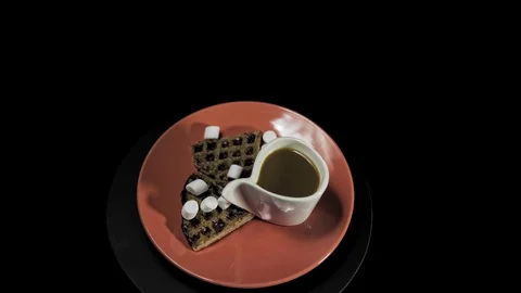 Waffle dark hearts on a red plate with coffee cup on black background. Stock Footage 101733097