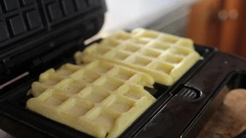 Waffle iron opens to reveal two golden brown waffles baking inside, with st.. Stock Footage 293716948