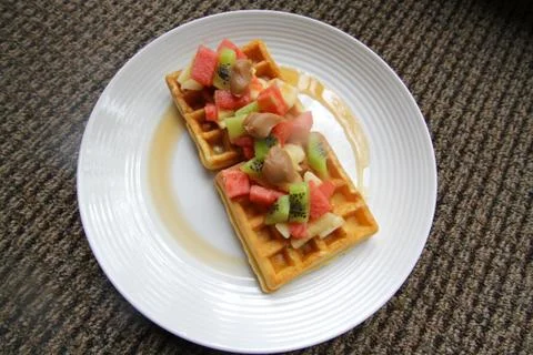 Waffles covered with fruit and maple syrup Stock Photos