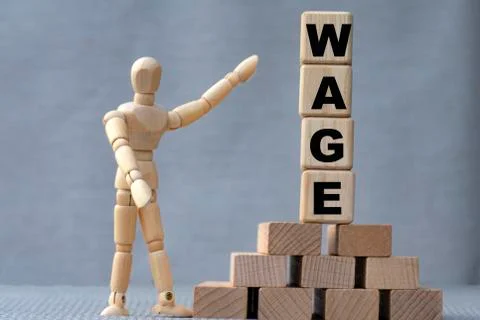 WAGE , the word is on cubes on a gray background, next to it is a wooden man. Stock Photos