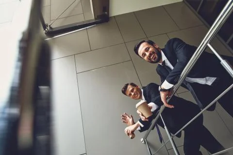 Waist up of cheerful colleagues smiling while drinking coffee Stock Photos