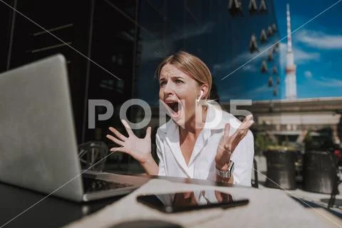 Waist up of nervous businesswoman with earpods working at laptop Stock Photos