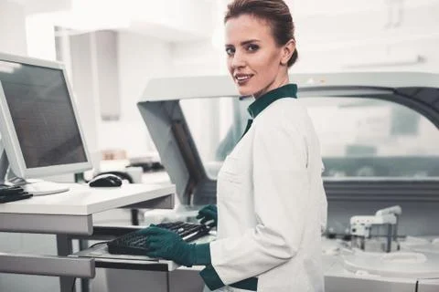 Waist up of pleased lab worker using computer Stock Photos