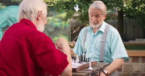 Waist up portrait view of the old two male friends on retirement playing chess Stock Footage 159092496