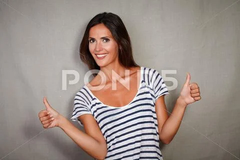 Waist up portrait of a young woman congratulating with thumbs up while lookin Stock Photos