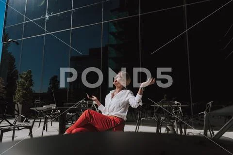 Waist up of smiling businesswoman keeping smartphone in arms and relaxing Stock Photos