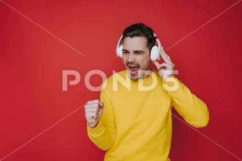 Waist up of young guy screaming while listening to music in studio Stock Photos