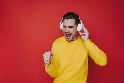 Waist up of young guy screaming while listening to music in studio Stock Photos