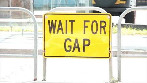 Wait for gap writing caption text street road sign on island in middle of road Stock Footage 252043426