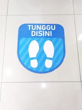"Wait Here" signage on the floor Stock Photos