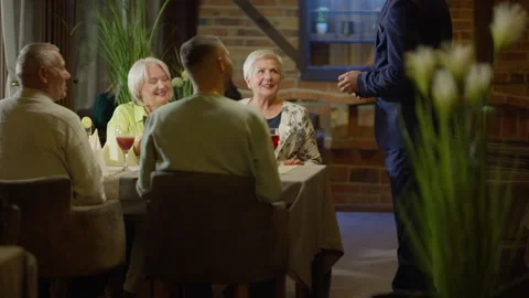 Waiter Approaching Restaurant Table with Two Men and Two Women to Take Order Stock Footage 280390511