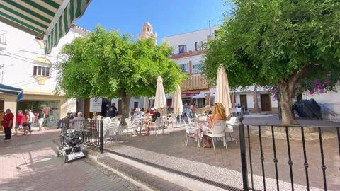 A waiter is bringing drinks to clients on a small Plaza with tables and chair Stock Footage 238806470