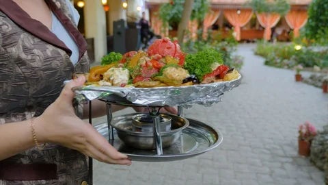The waiter delivers to the table cooked in a cauldron vegetables. Stock Footage 124731726