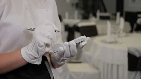 A waiter in gloves writes down an order in a notebook in a restaurant. Stock Footage 168248676