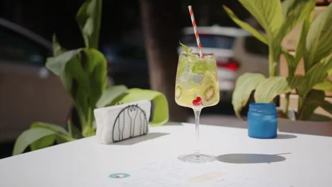 Waiter hand puts on a table beautiful refreshing fruit cocktail in a summer city Stock Footage 246320265