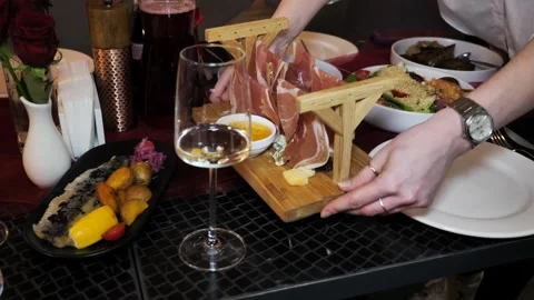 Waiter hands placing a prosciutto platter on served restaurant table. Stock Footage 340533124