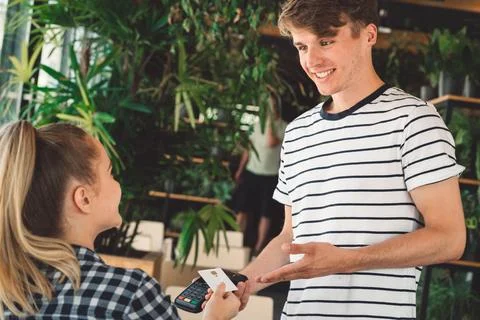Waiter holding card reader while woman pays for her coffee with credit card Stock Photos