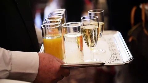 Waiter holding a tray with champagne glasses and other beverages Vidéo 73331553