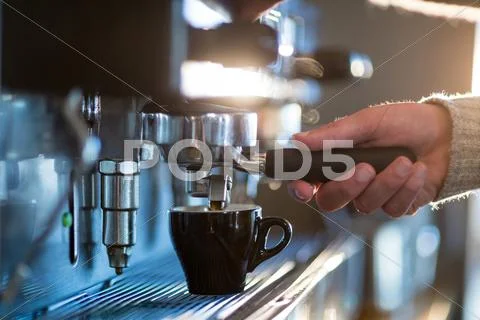 Waiter Making Cup Of Coffee At Counter In Kitchen