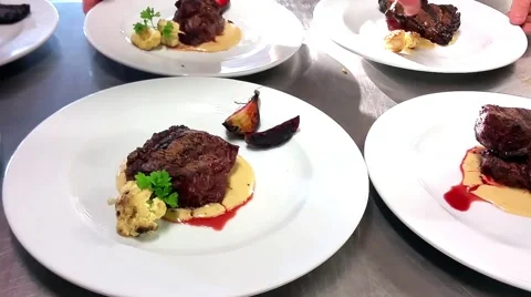 Waiter picking up and serving black angus entrecote dish plates to customers Stock Footage 56441752