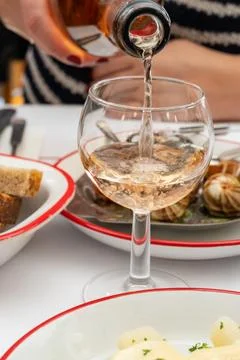 Waiter pours cold rose wine into an elegant glass at a classic Parisian bis.. Stock Photos