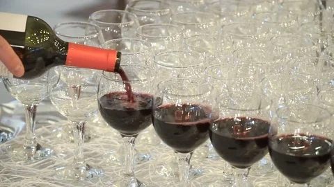 The waiter pours red wine in the rows of glasses at the festival Stock Footage 78162701