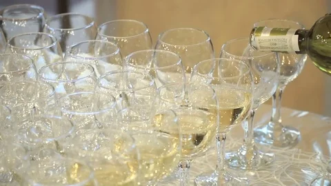 The waiter pours red wine in the rows of glasses at the festival Stock Footage 78162976
