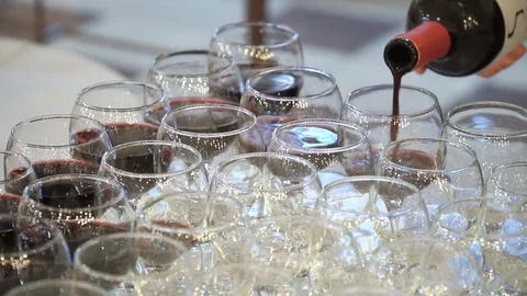 The waiter pours red wine in the rows of glasses at the festival Stock Footage 78163517