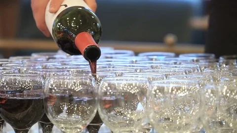 The waiter pours red wine in the rows of glasses at the festival Stock Footage 78163815