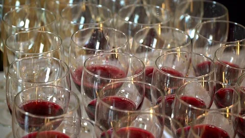 The waiter pours red wine in the rows of glasses.On the table is a bunch of red Stock Footage 92498786