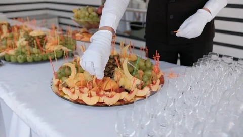 The waiter prepares a serving table. String fruit on a skewer Stock Footage 129084983