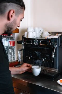 Waiter preparing a coffee at the bar's coffee machine. Vertical Stock Photos