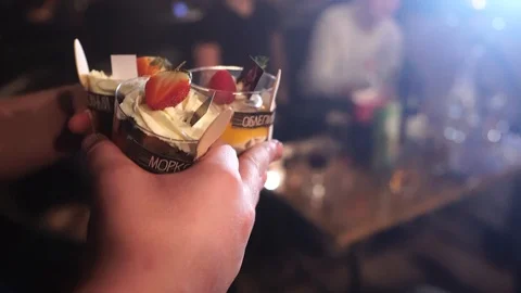 Waiter puts desserts on the table to the visitors of the cafe Stock Footage 90347645