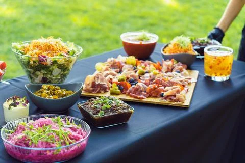 The waiter puts the dish on the table with appetizers for a buffet in the gar Stock Photos