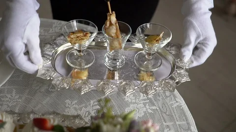The waiter puts a silver tray with snacks on the table. Stock Footage 95911369