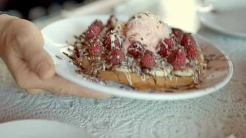 The waiter puts on the table chocolate waffles with raspberries and ice cream Stock Footage 122625540