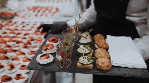 The waiter puts on a tray of canapes with cherry and strawberry. Catering Stock Footage 104373532