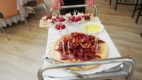 A waiter rolls a table with snacks at a party in a restaurant. Large plate with Stock Footage 263418829