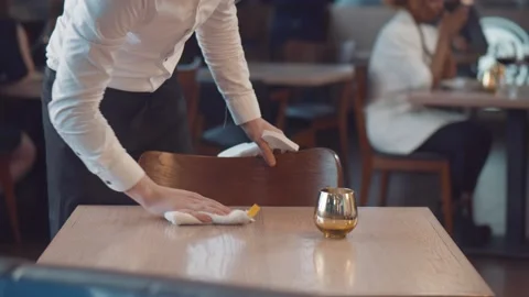 Waiter cleaning the table with spray disinfectant on table in